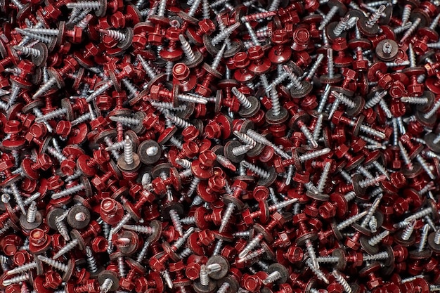 Bunch of galvanized selfdrilling screws with washer and red hexagonal head hardware background