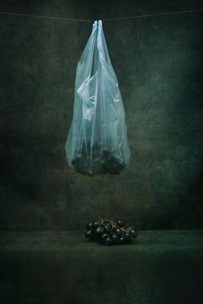 A bunch of grapes in a cellophane bag on a string on a dark background