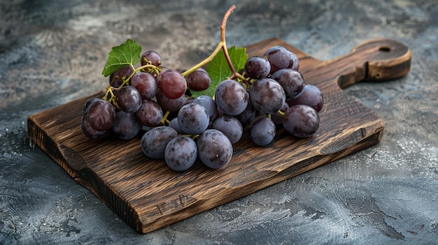 a bunch of grapes on a wooden board with a leaf on it