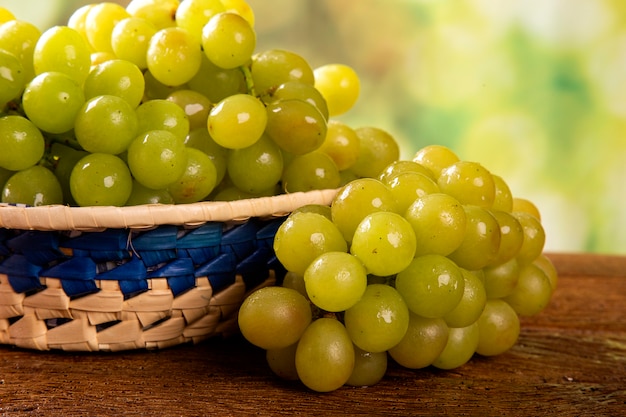 Bunch of green grapes, fruits of autumn, a symbol of abundance on rustic wood background.