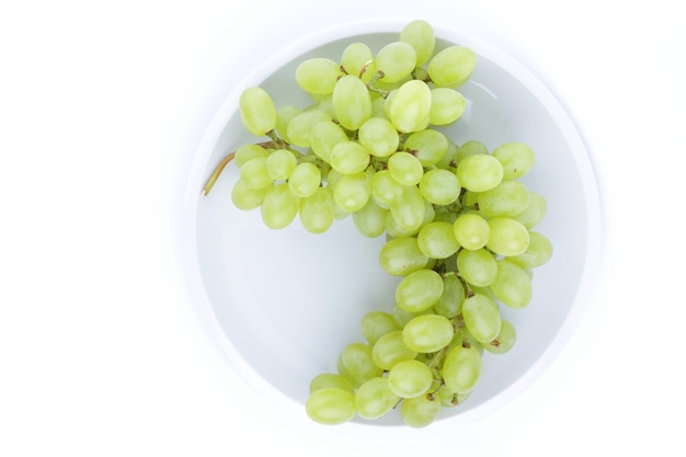 A bunch of green juicy grapes on a white plate isolated on a white background Big tasty sweet grapes on a white plate closeup