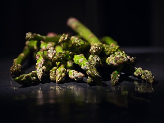 Bunch of green vitamin asparagus stems reflecting on gray table prepared for cooking vegan dish