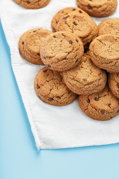 A bunch of oatmeal cookies with chocolate on a napkin on a blue background. Top view, free space