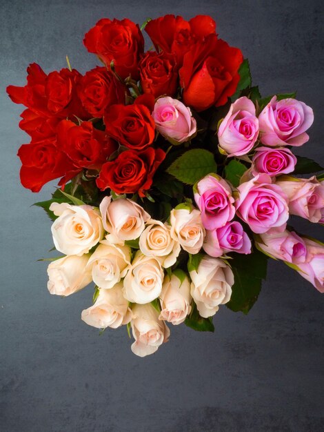 Bunch of opened roses of different colors on grey concrete table