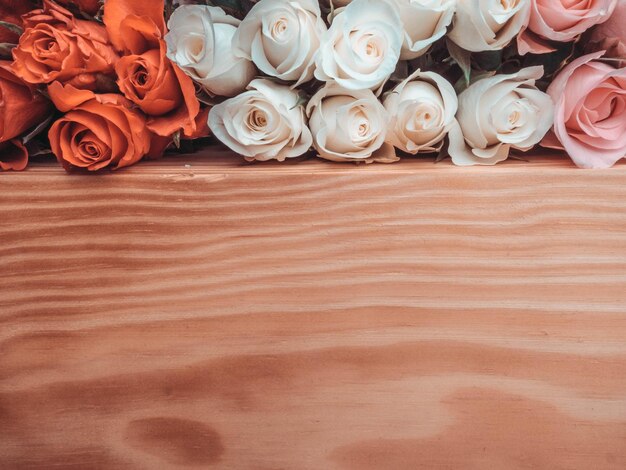 Bunch of opened roses of different colors on wooden surface selective focus