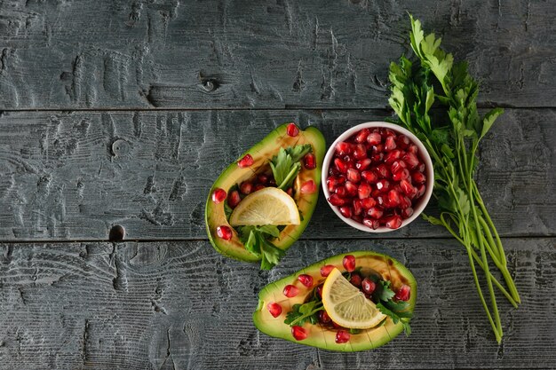 A bunch of parsley, a white bowl with pomegranate seeds and avocado on the village table