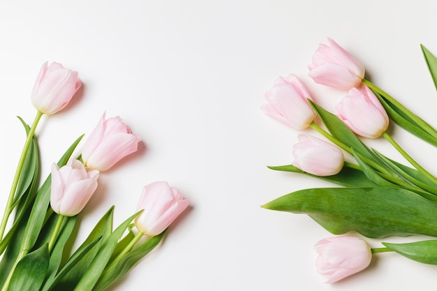 a bunch of pink tulips with green leaves on a table