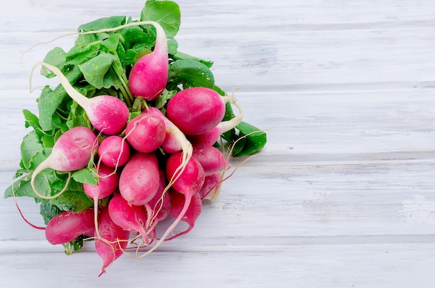 Photo bunch of radishes with leaves on a wooden table