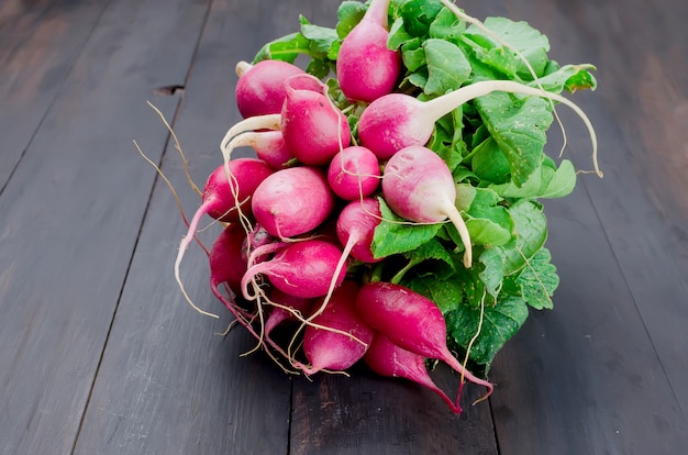 Photo bunch of radishes with leaves on a wooden table