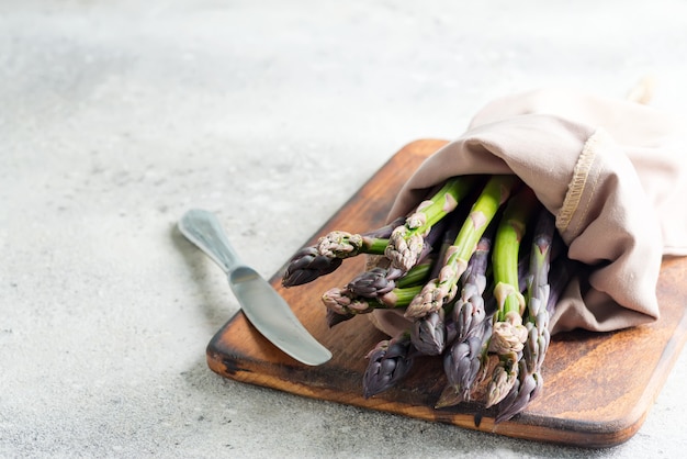 Bunch of raw organic asparagus spears on board ready for cooking healthy diet food on light grey marble.