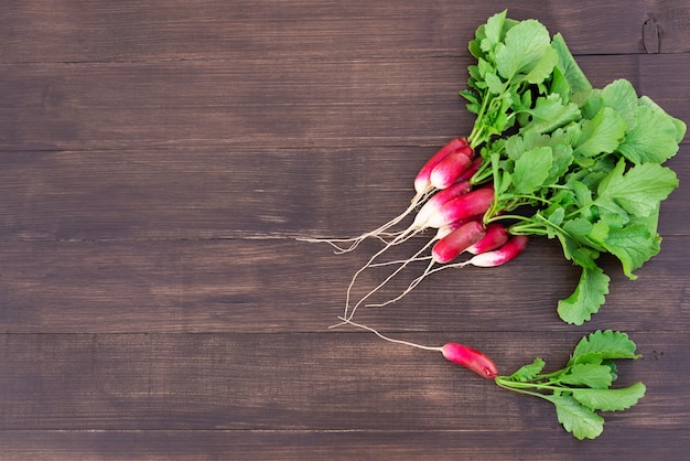 A bunch of red radishes on a wooden table horizontal orientation copy space top view