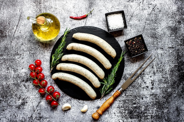 A bunch of sausages on a black table with spices and olive oil.