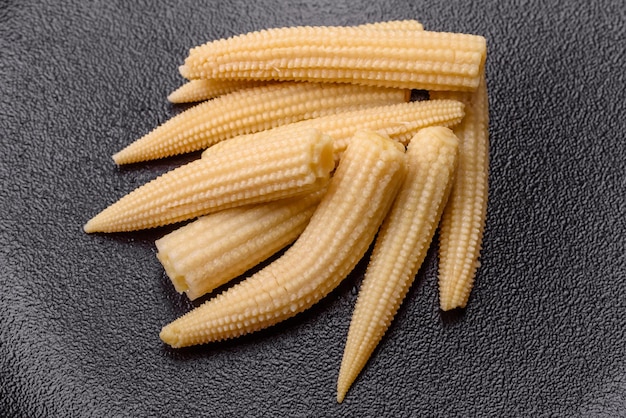 A bunch of small white canned corn on a dark concrete background