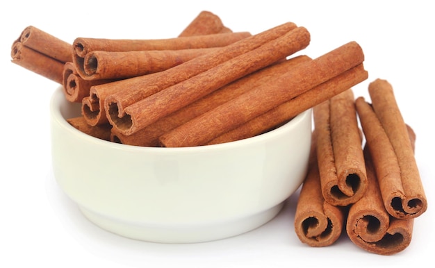 Bunch of some fresh aromatic cinnamon in a bowl over white background