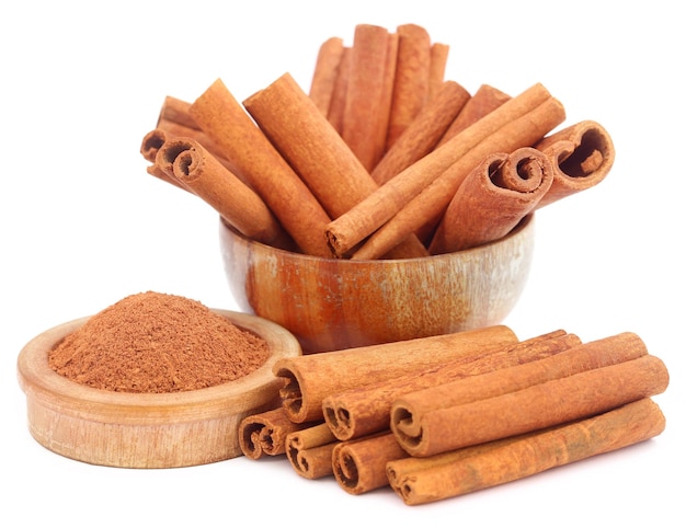 Bunch of some fresh aromatic cinnamon with powder spice over white background