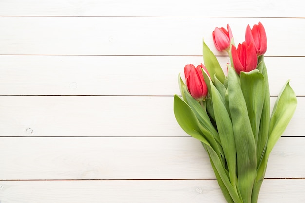 Bunch of spring tulips over white wooden background, top view flat lay