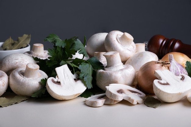 Bunch of whole raw fresh champignons with other cooking ingredients on table or background Mushrooms...