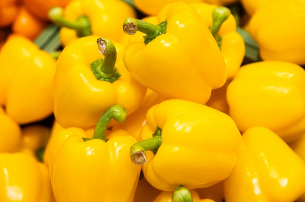 Bunch of yellow peppers in farmer's market or grocery store. Vegetable surface. Spicy and sweet plant for sustainable diet.