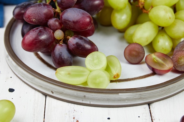 Bunches of fresh ripe green and red grapes on a wooden table