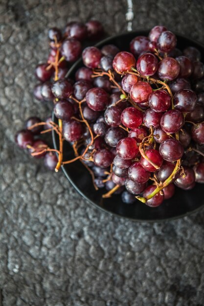 Bunches of red grapes on old black  wooden table . Symbol of autumn cornucopia, top view