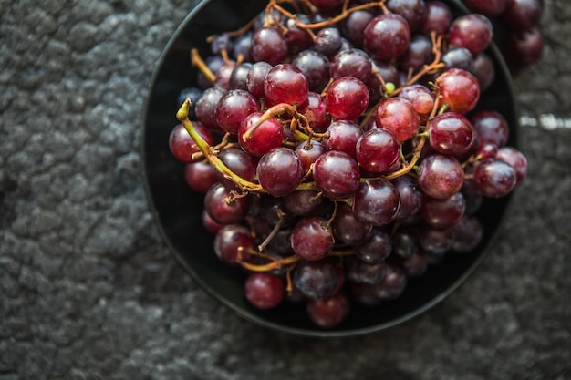 Bunches of red grapes on old black  wooden table . Symbol of autumn cornucopia, top view