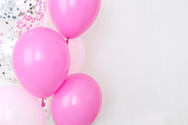 A bundle of pink and transparent air balloons with silver confetti copy space for your text tender pastel colors for a girlish party