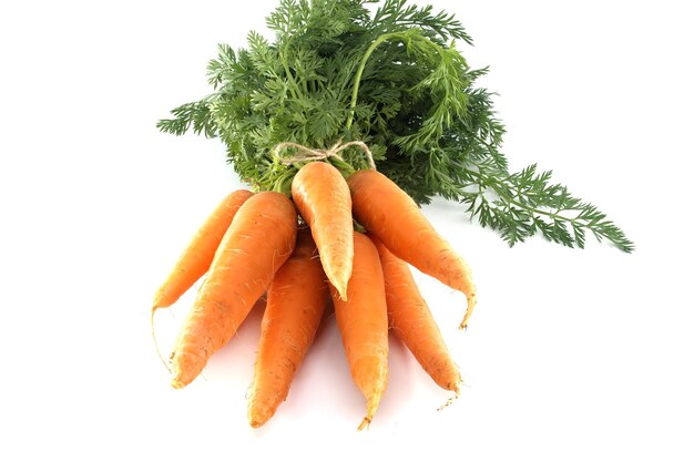 Bundle of vibrant orange carrots with green leafy tops carrots are tied together with twine