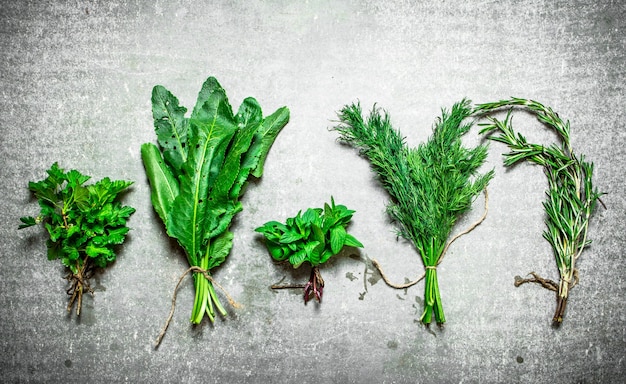 Bundles of different herbs. On the stone table.