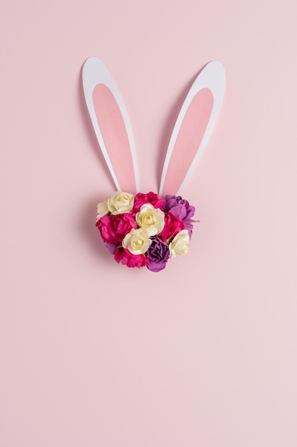 Bunny or rabbit ears with spring flowers on pastel pink background Happy Easter minimal concept Flat lay