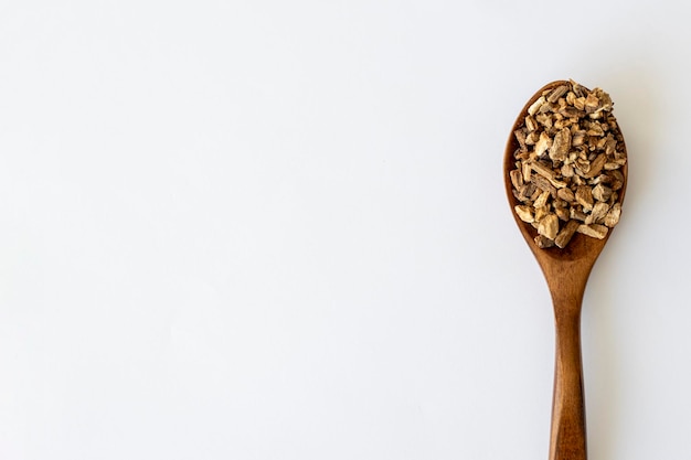 Burdock Root Herb Herbal Medicine Dried Finely Chopped Root in a Wooden Spoon on a White Background with Copy Space