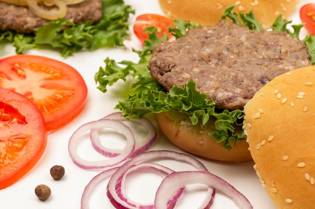 Burger bun on lettuce leaf Chopped tomatoes and onions on table