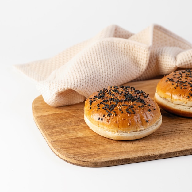 Burger buns with sesame seeds on a wooden board on a white background, close-up