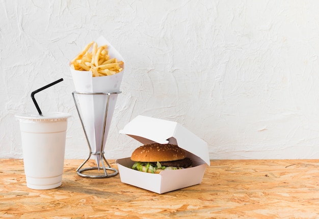 Photo burger; french fries and disposal cup on wooden table top