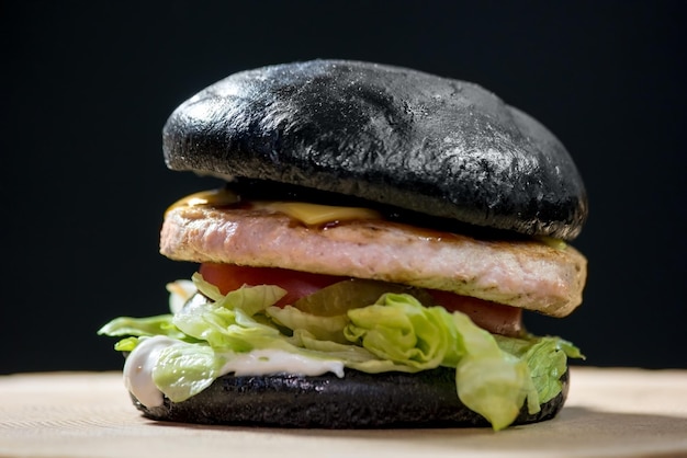 Burger with black bun hamburger on dark background