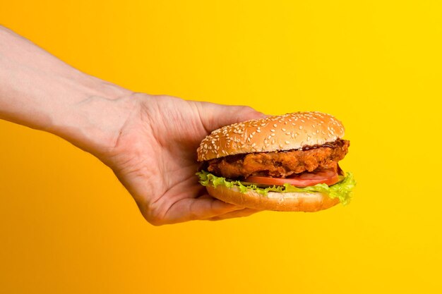 Burger with chicken and vegetables burger with chicken on a yellow background