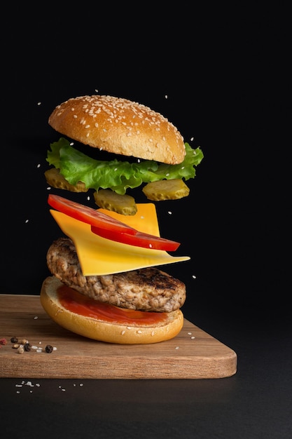 burger with flying ingredients on black background