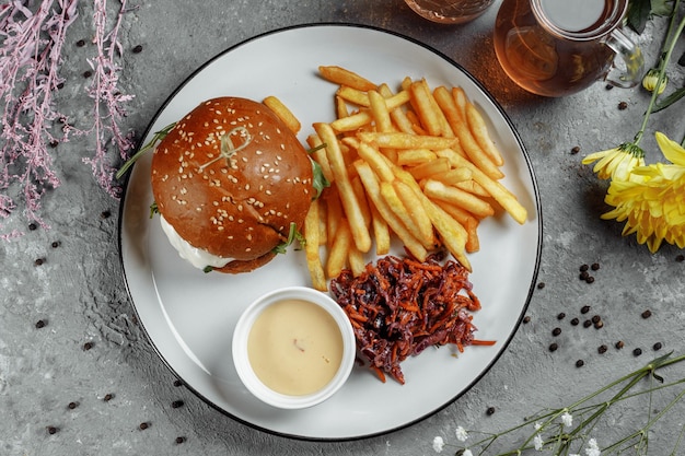 Burger with fries and sauce on a white plate