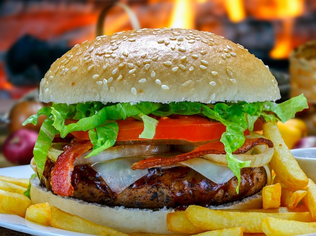 Burger with grilled meat tomato onion lettuce bacon and french fries