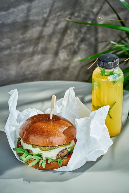 A burger with mozzarella pesto and arugula on white parchment Closeup selective focus