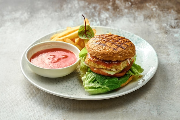 Burger with vegetables and chicken in a plate. Close-up, selective focus. A side dish of French frie