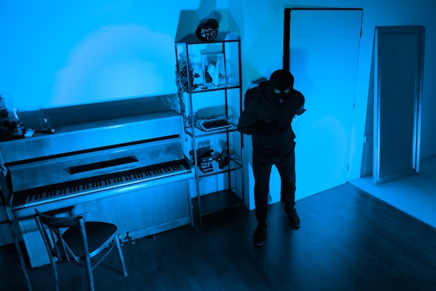 Burglar with full backpack examining dark room