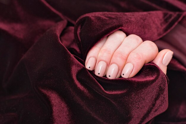 Photo burgundy velvet fabric in a female hand. close up