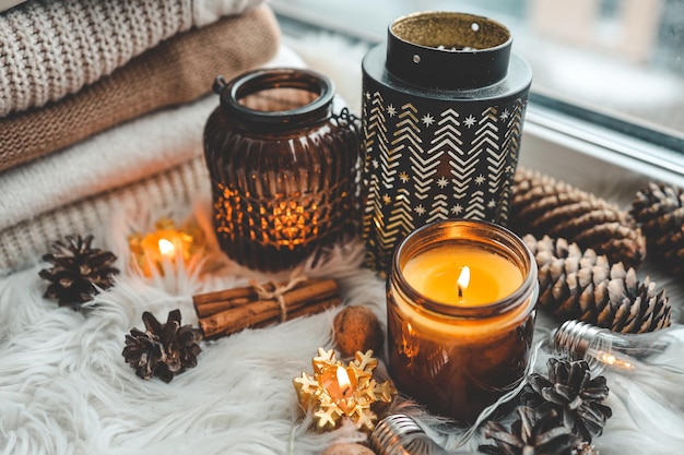 A burning candle and beautiful candlesticks in Scandinavian style in a home interior