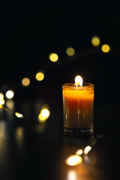 Burning candle on black background with bokeh Memorial Day