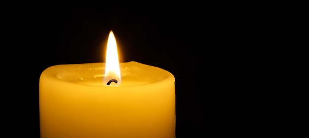 A burning candle on the black backgrounds