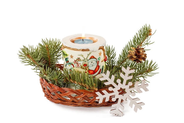 Burning candle cone and natural fir tree branches in wicker basket