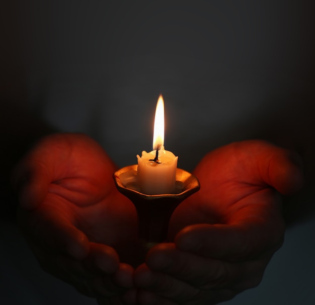 Photo burning candle in a mans hand religion concept