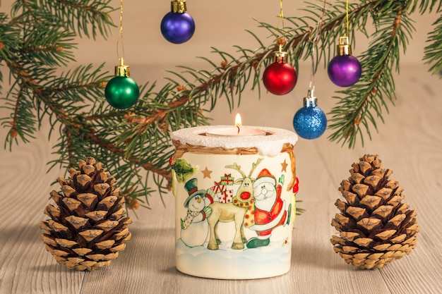 Burning candle and natural fir tree branches with Christmas ornament