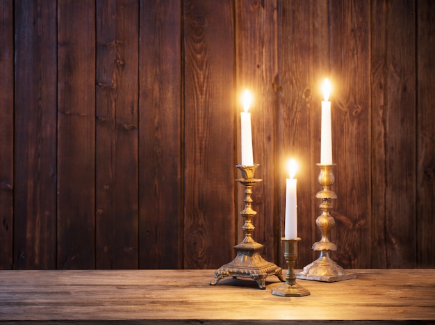 Burning candle on old wooden wall