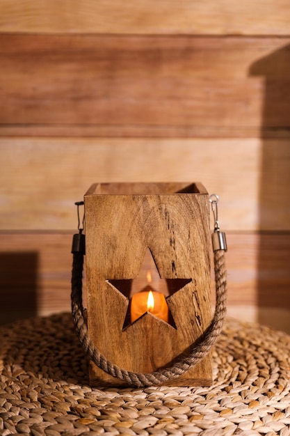 Burning candle in wooden holder on table